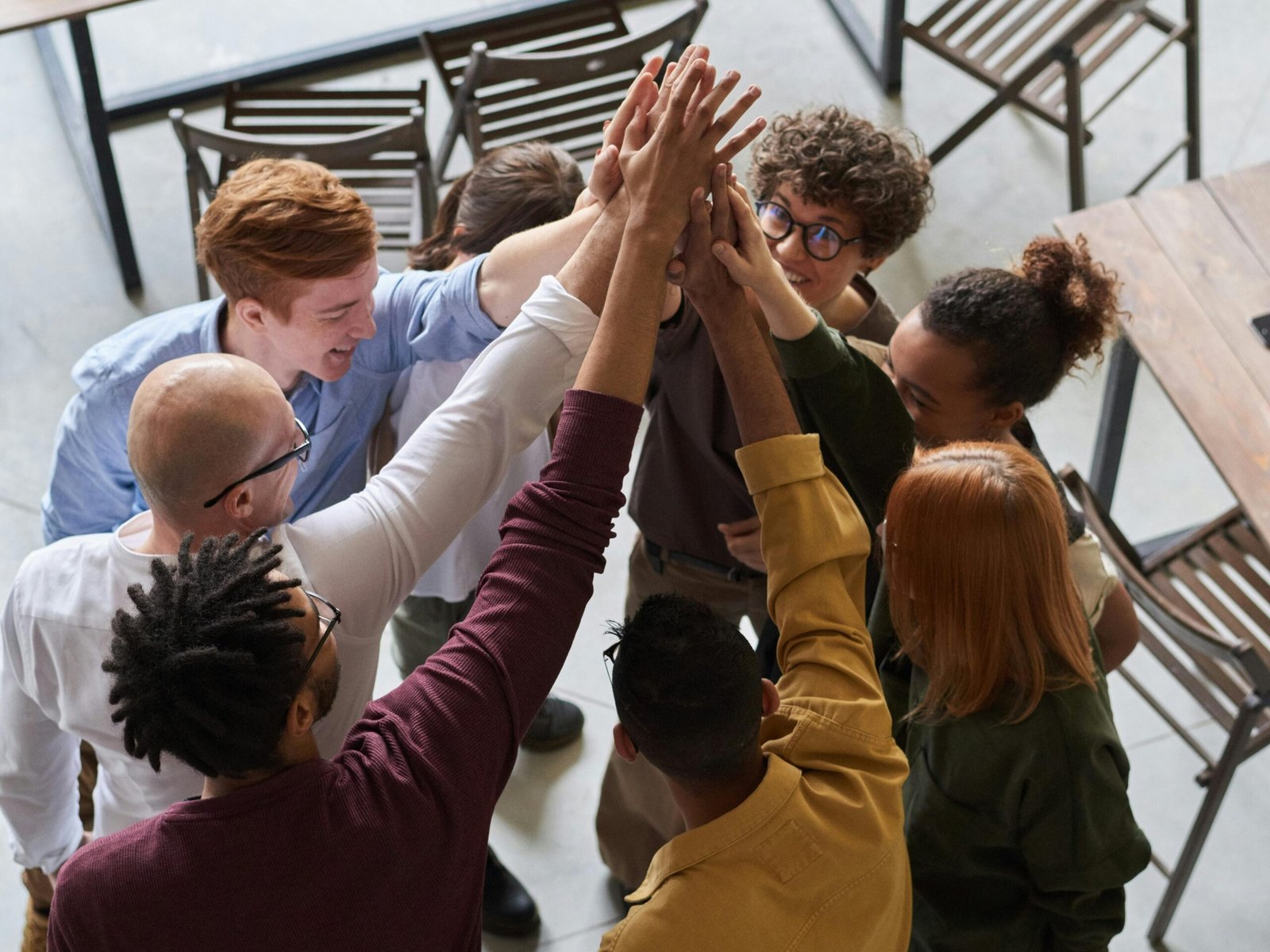 A diverse group of professionals high-fiving in a modern office, showcasing teamwork and collaboration.